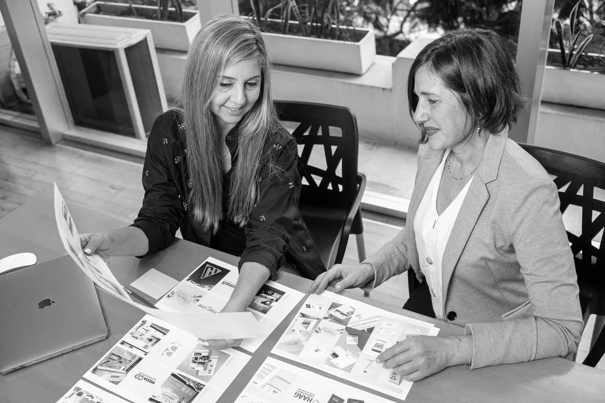 Muriel y Vale en mesa de trabajo analizando la estrategia visual y comunicacional de marca